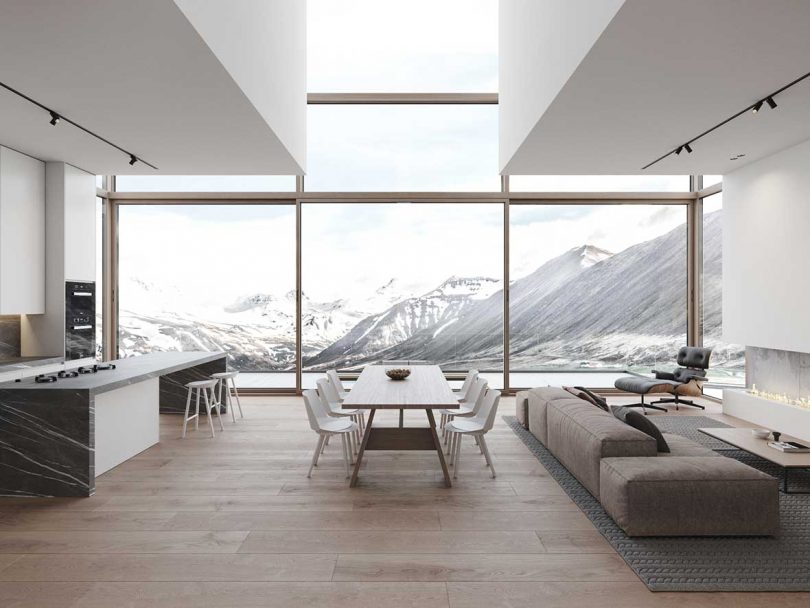 modern living space with living room, kitchen, and dining room with glass wall of windows looking out to snowy mountains