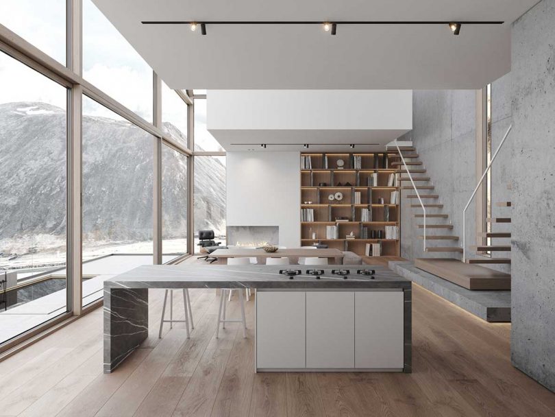 modern living space with living room, kitchen, and dining room with glass wall of windows looking out to snowy mountains
