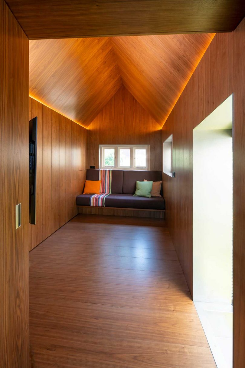 narrow room with wood paneling on all surfaces with a built-in upholstered bench