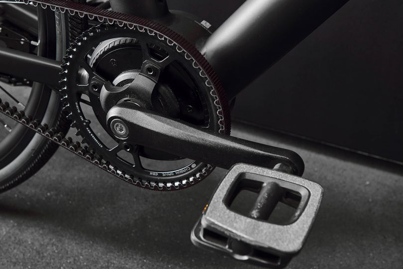 Detail of bike pedal, carbon belt drive and motor, all in matte black finish.