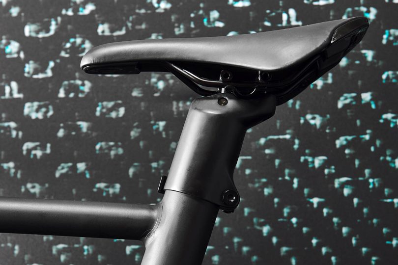 Detail of bicycle seat post and narrow, racer-style seat in matte black.