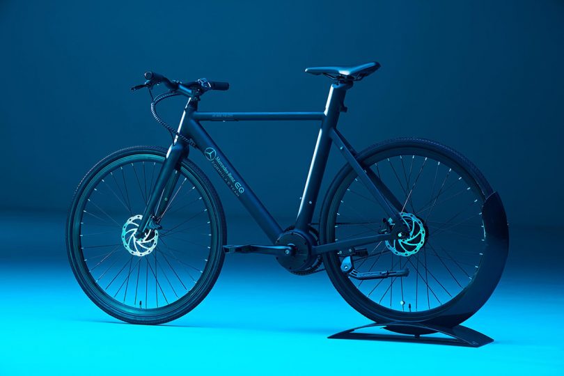 eBike set on stand against an aqua to dark blue gradient backdrop. 