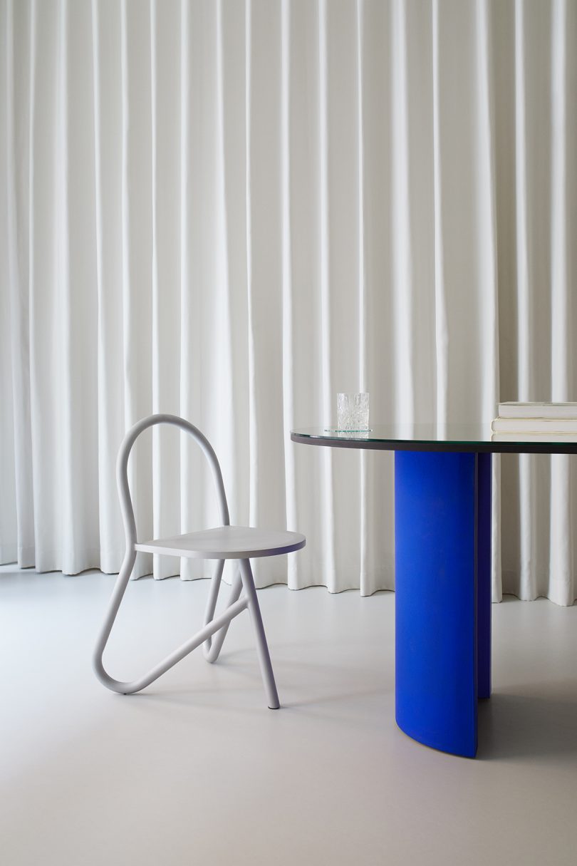 tubular chair and dining table in front of white pleated background