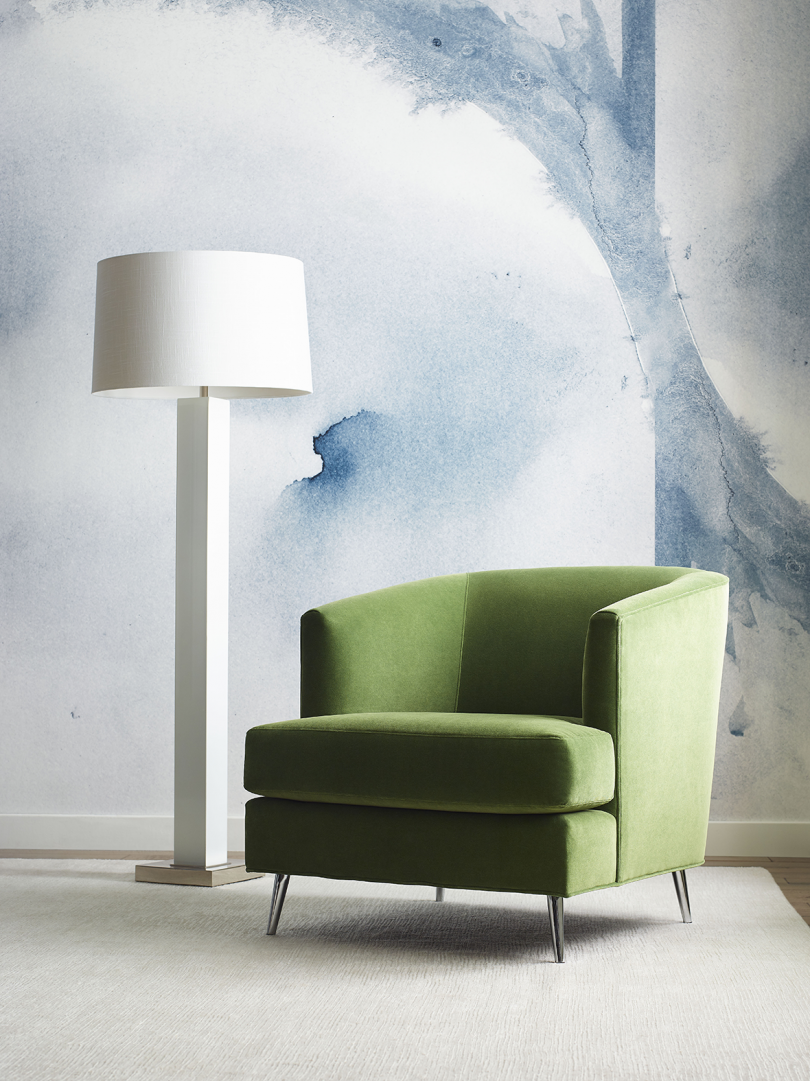 green armchair and floor lamp in front of wall featuring large blue watercolor wallpaper