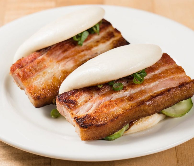 two pork belly rolls on white plate
