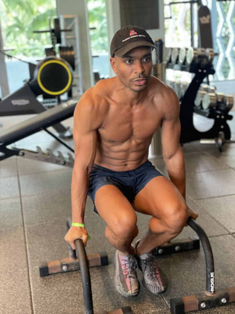 brown-skinned man wearing shorts and baseball hat while working out