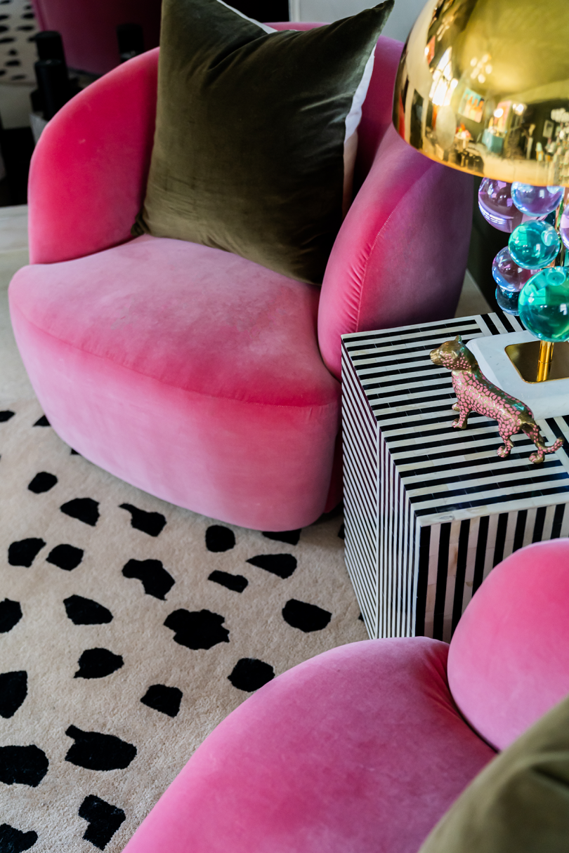 living space with hot pink armchairs, spots rug, and striped side table