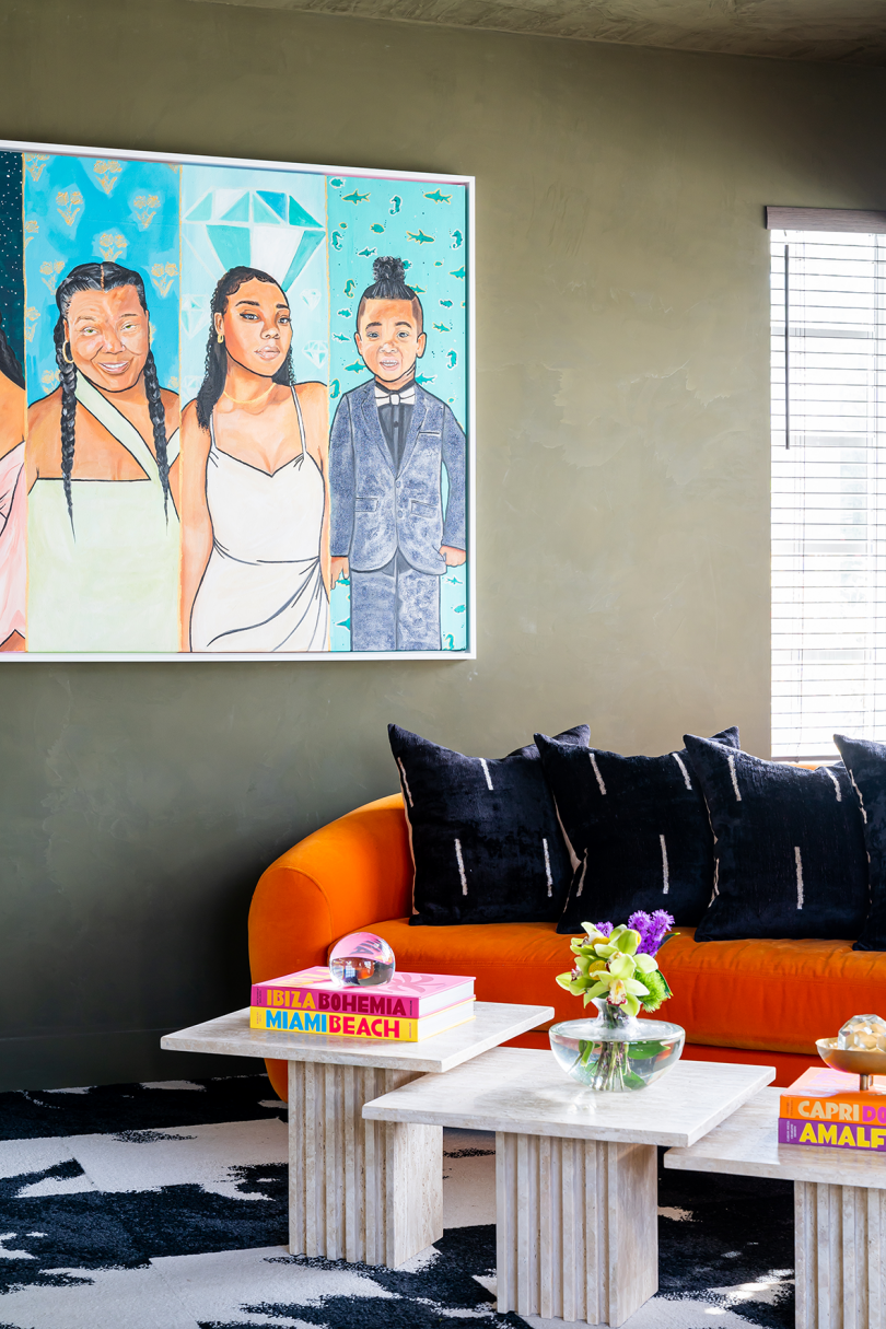 living space with bright orange sofa and painting of three brown-skinned women