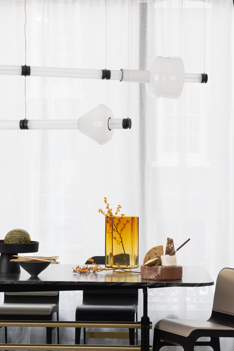 two horizontal unlit pendant lights hanging over a dining table