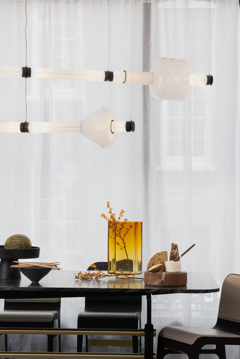 two horizontal lit pendant lights hanging over a dining table