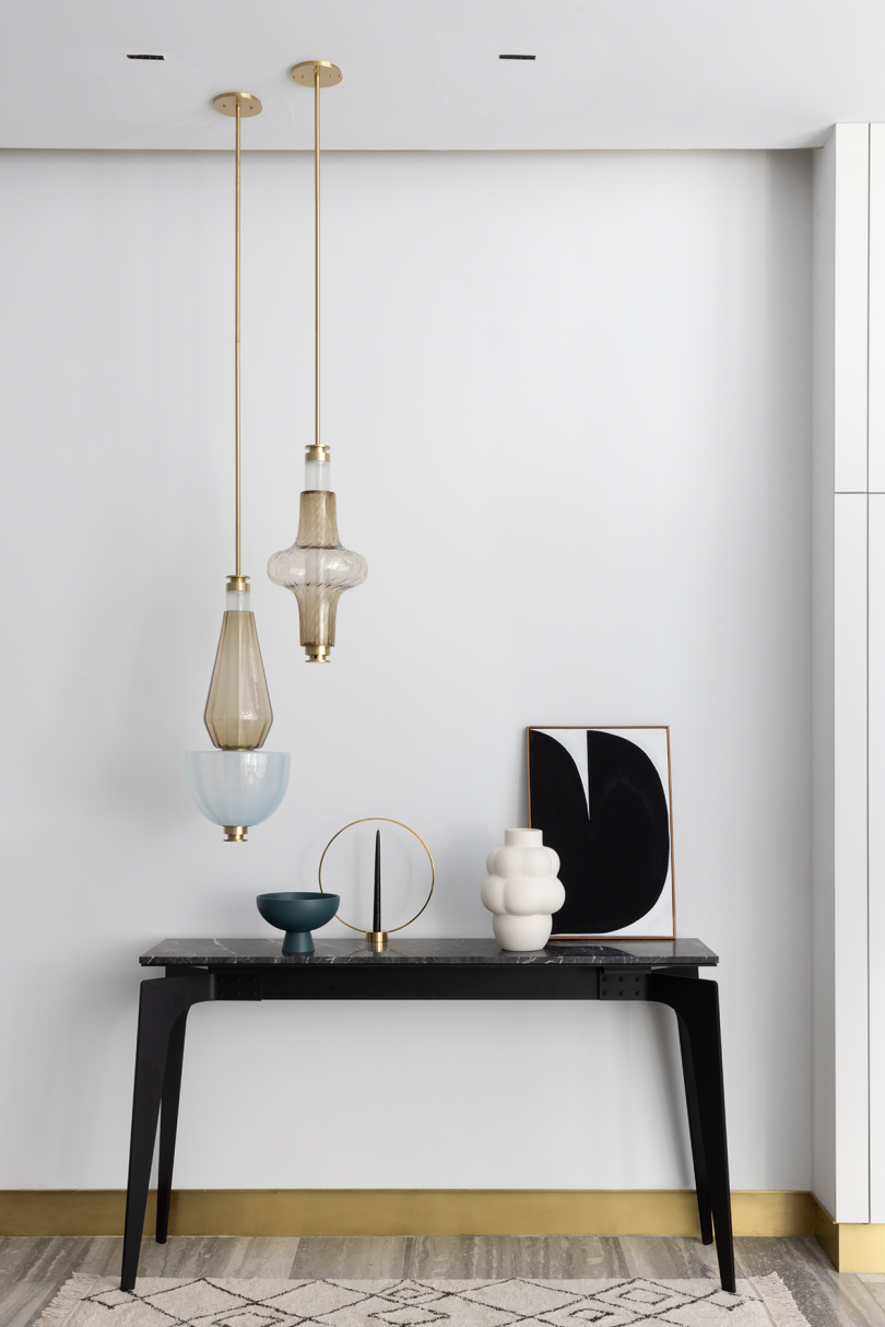 two unlit light pendants hanging above styled console table