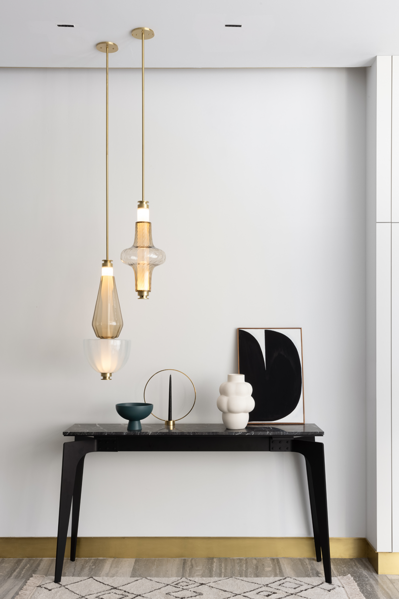 two lit light pendants hanging above styled console table