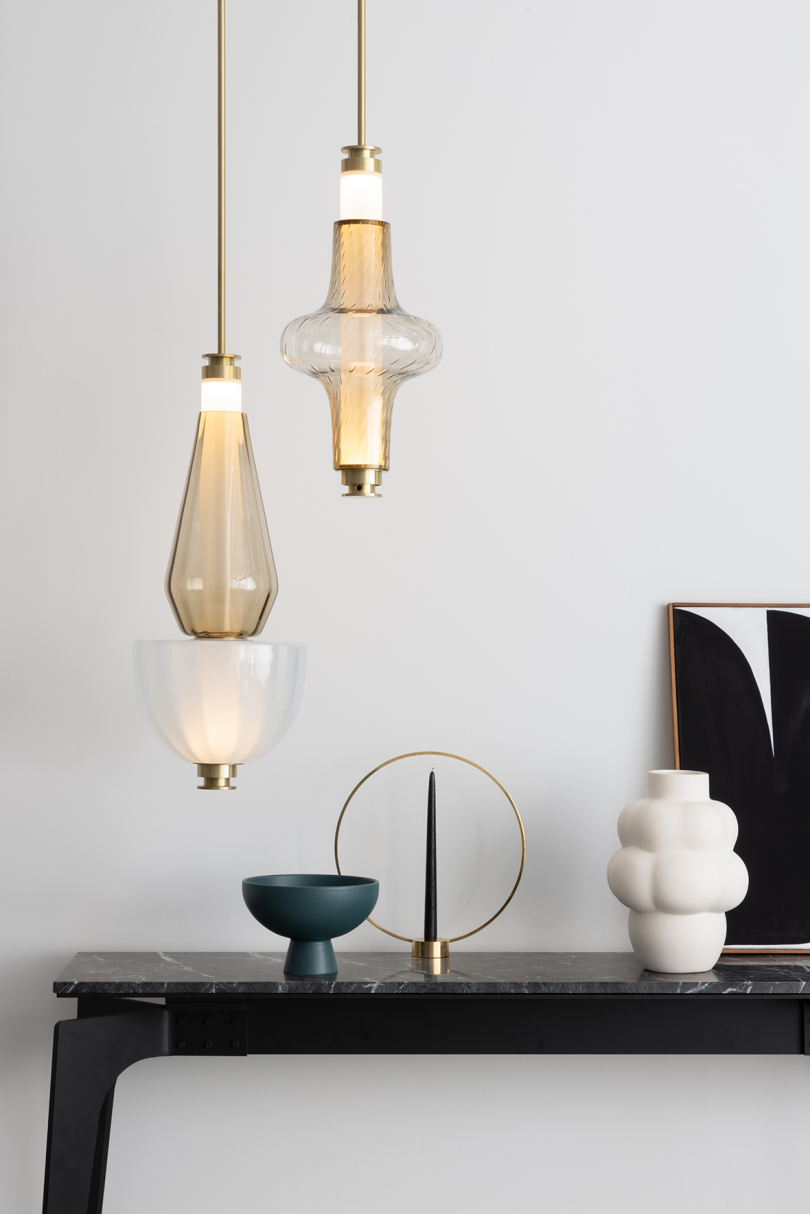 two lit light pendants hanging above styled console table