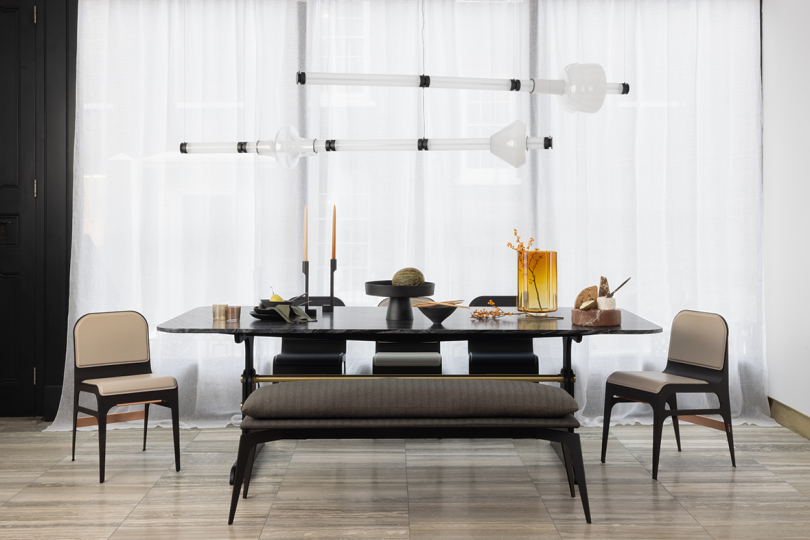 two horizontal unlit pendant lights hanging over a dining table and seating