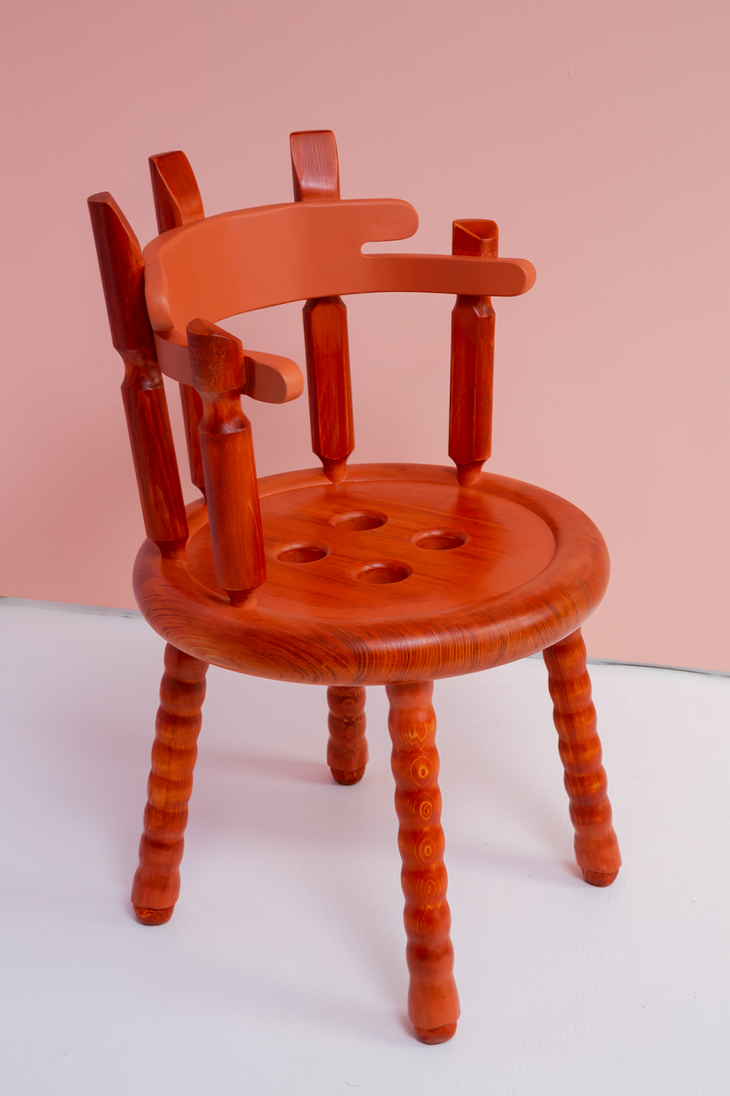 red wooden armchair on white floor in front of light pink wall