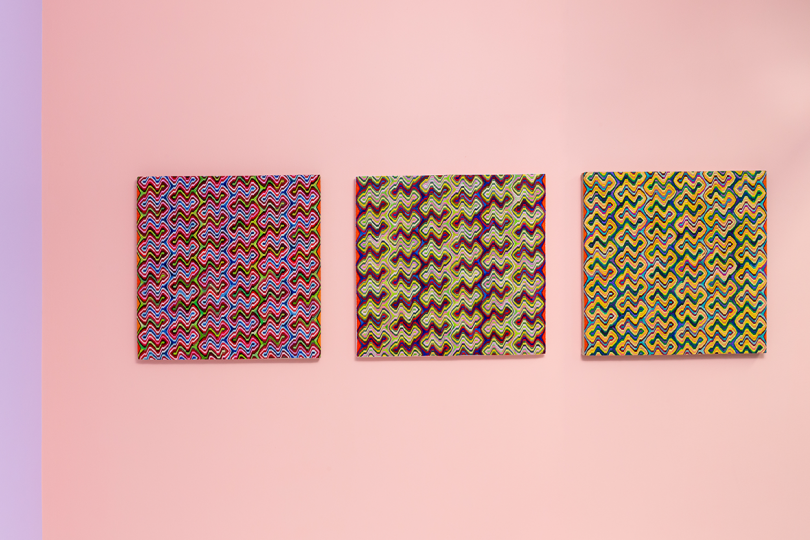 three square patterned artworks hanging on light pink wall