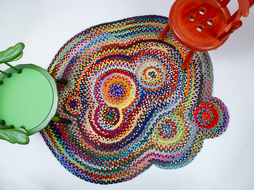 multicolored textile rug with green and red wood armchairs sitting on the edges