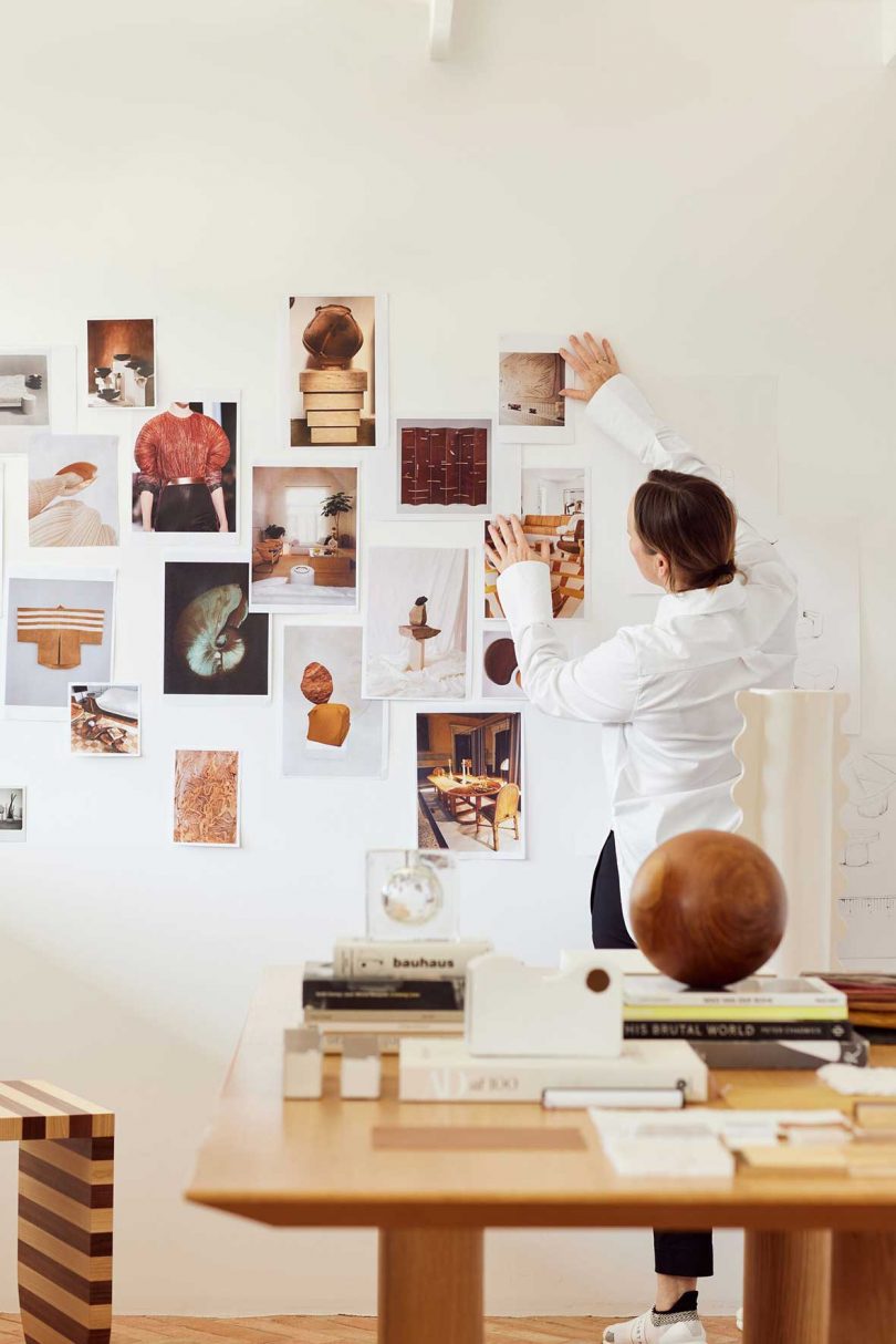 Designer faces wall while hanging sketches on inspiration board