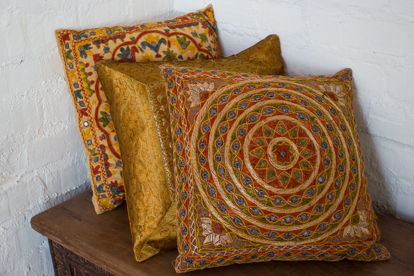 three Indian textile pillows in shades of gold
