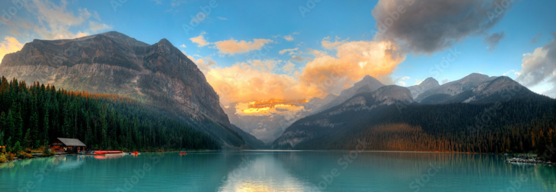 panoramic landscape of two mountains and a large bod off water against a cloudy blue sky