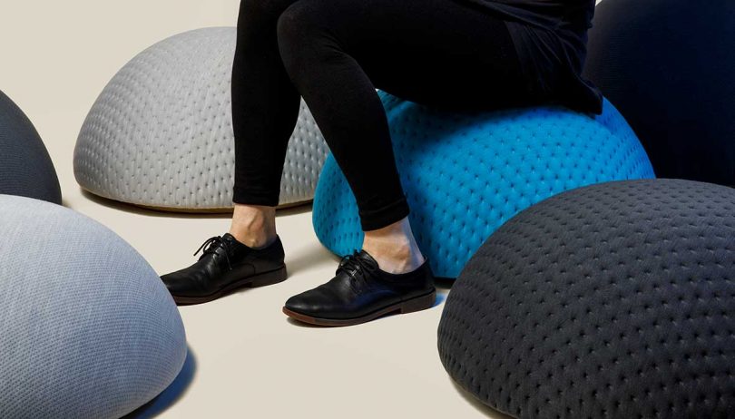 legs in black shoes and pants sitting on a blue pouf