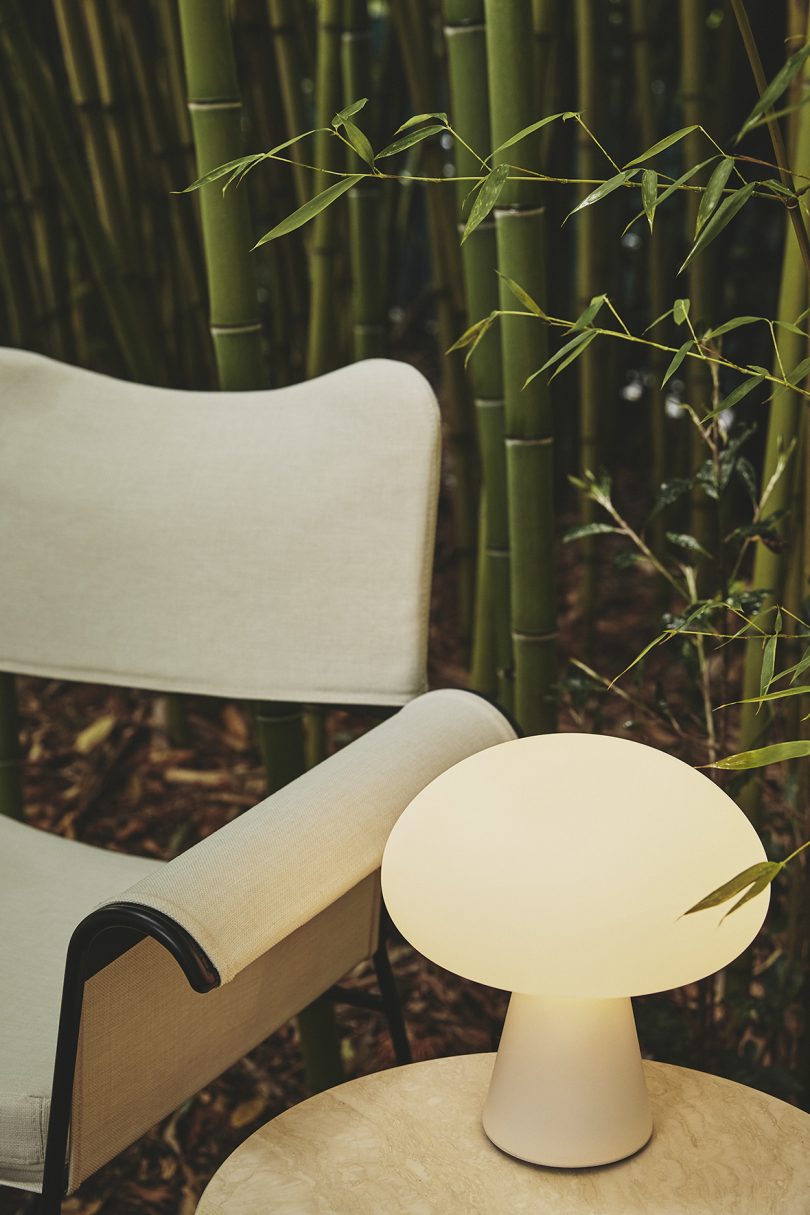 lit mushroom-shaped lamp sitting on small table next to outdoor armchair