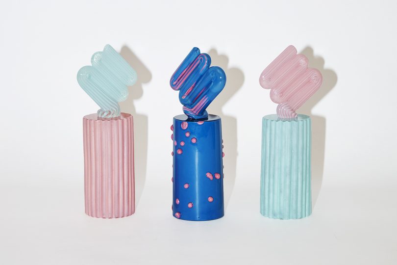three blue and pink art objects lined up in a row on a white background