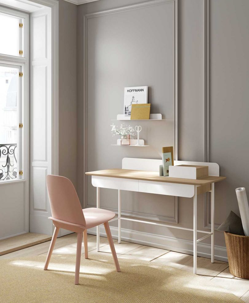 styled white and light wood desk with chair in front of light grey wall