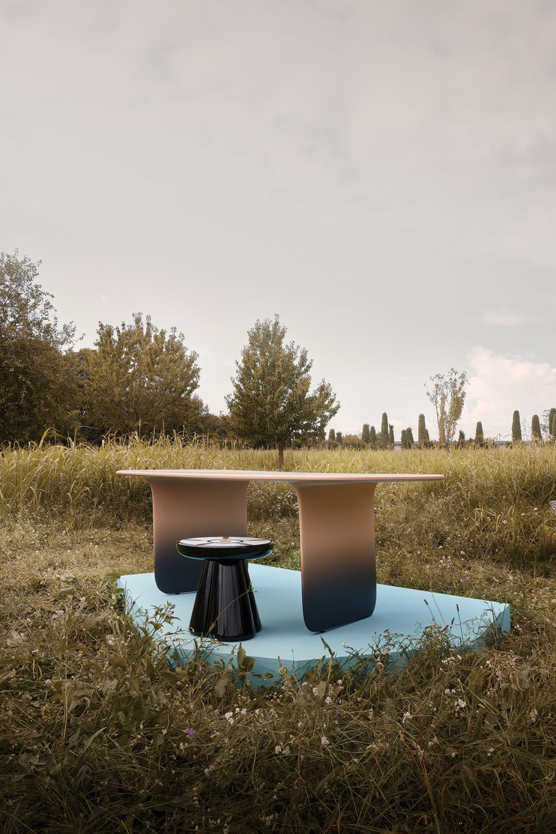 gradient dining table and small round table on a light blue pedestal in the middle of a field