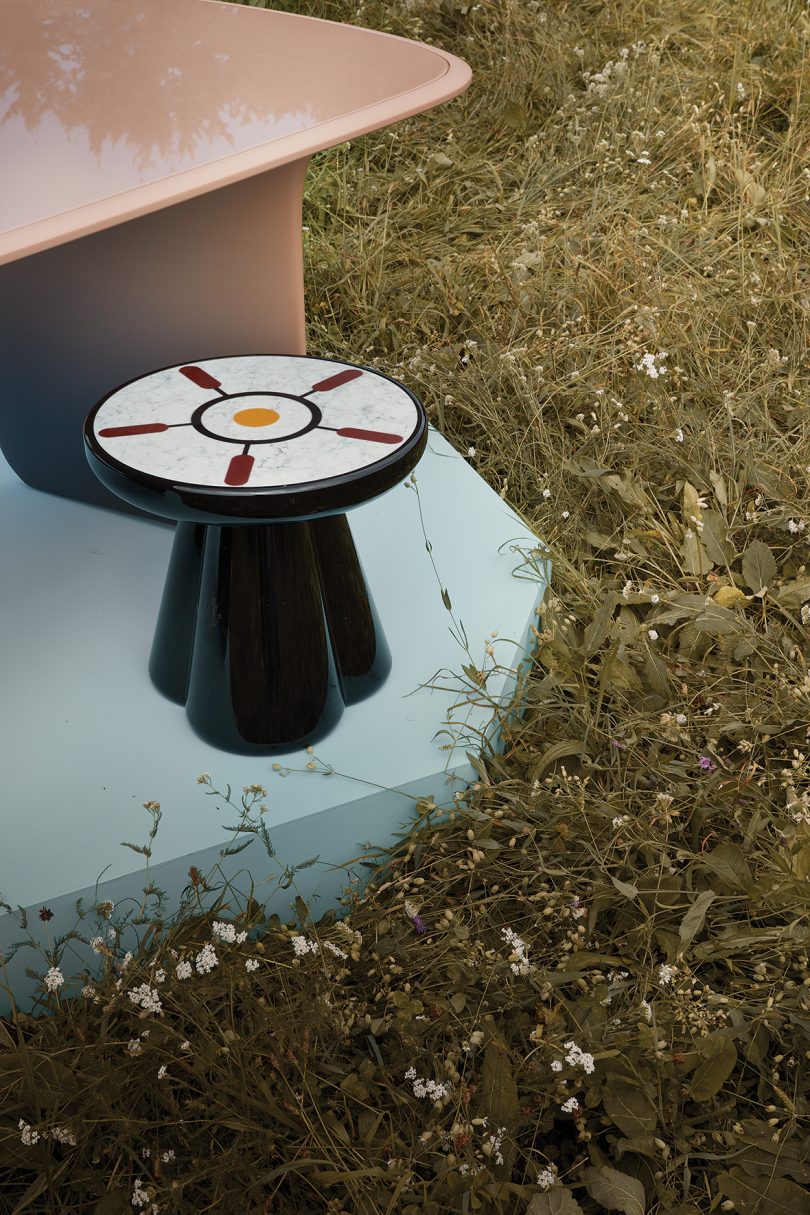 detail of gradient dining table and small round table on a light blue pedestal in the middle of a field