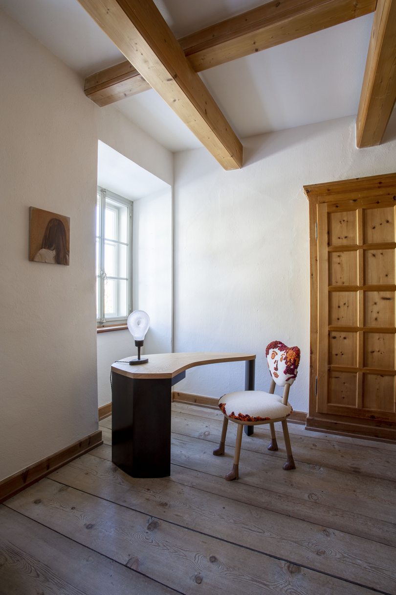 living space with white walls, a large wooden door, curved desk, and desk chair