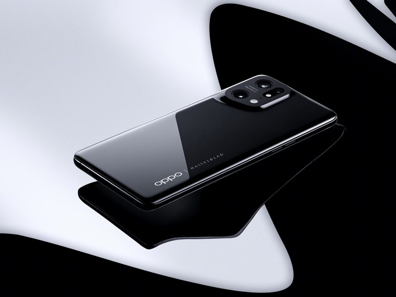 Black Oppo Find X5 smartphone against shiny black surface.