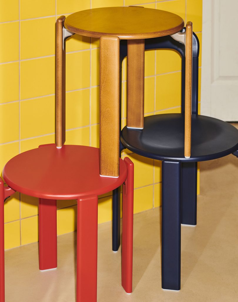 three colorful stools stacked in a pyramid in front of a yellow wall
