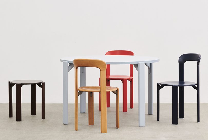 round dining table surrounded by three colorful enamel chairs and one stool