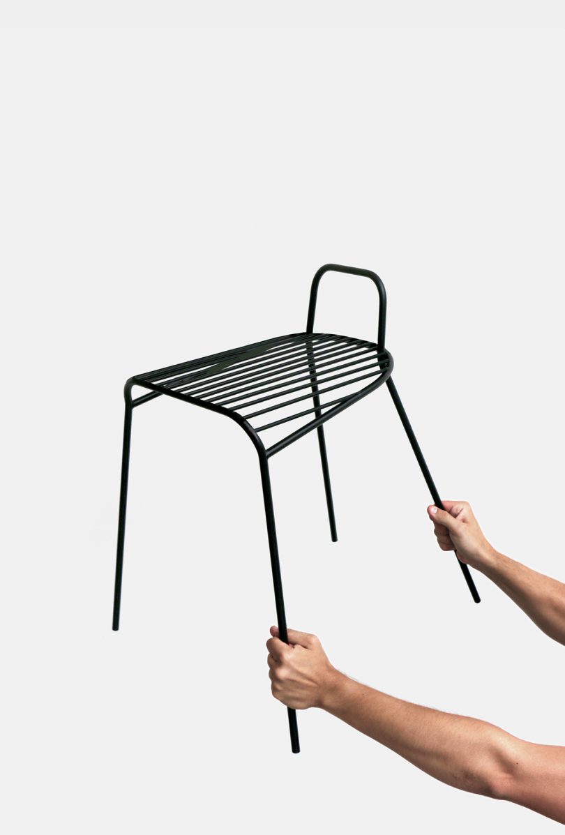 black chair being held up by two arms against white background