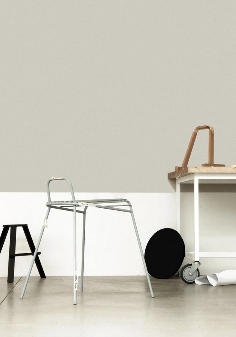 chair with table and other styled objects against white and grey wall