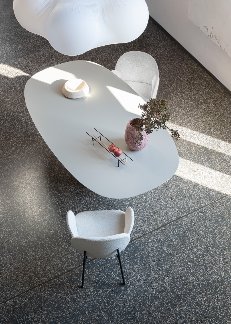 overhead view of white oval shaped dining table with two white armchairs