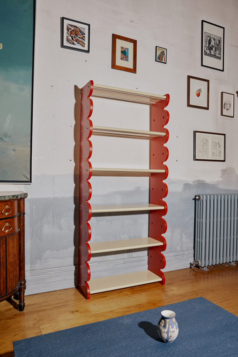 tall red bookshelf with. natural wood shelves in styled interior space