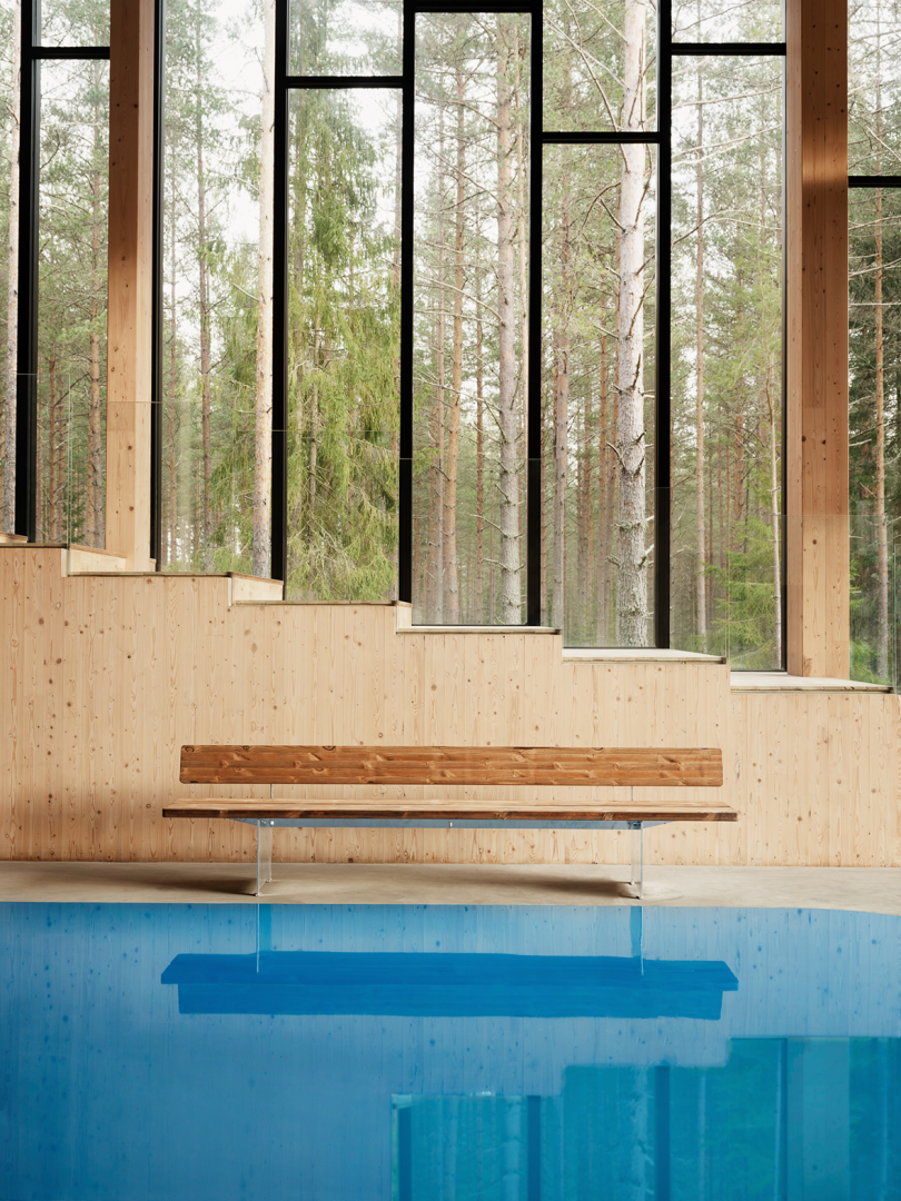 long wood bench in front of light wood wall with windows