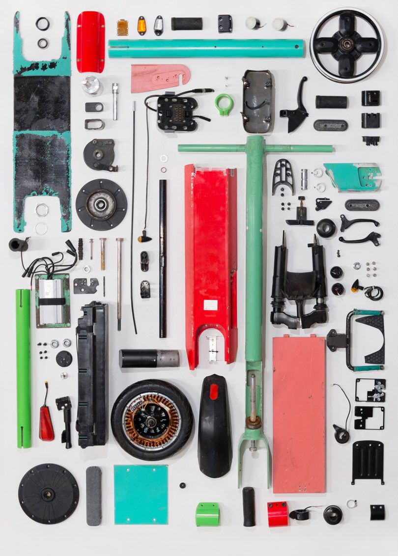 Disassembled electric scooter with all parts laid upon the ground.