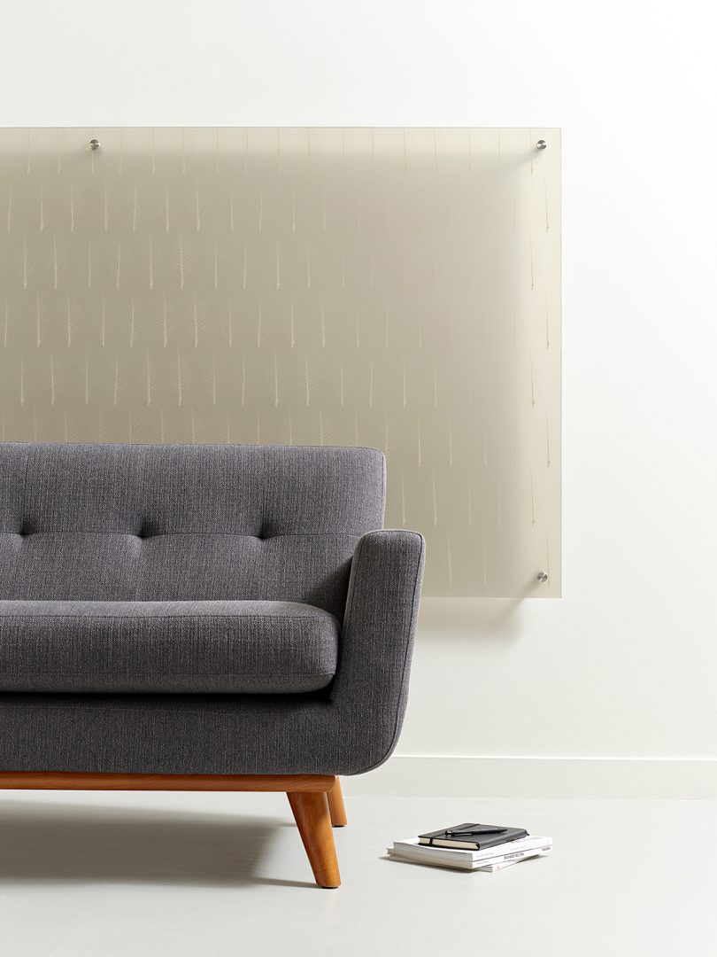 half of a modern grey couch with light grey patterned panel hanging behind it