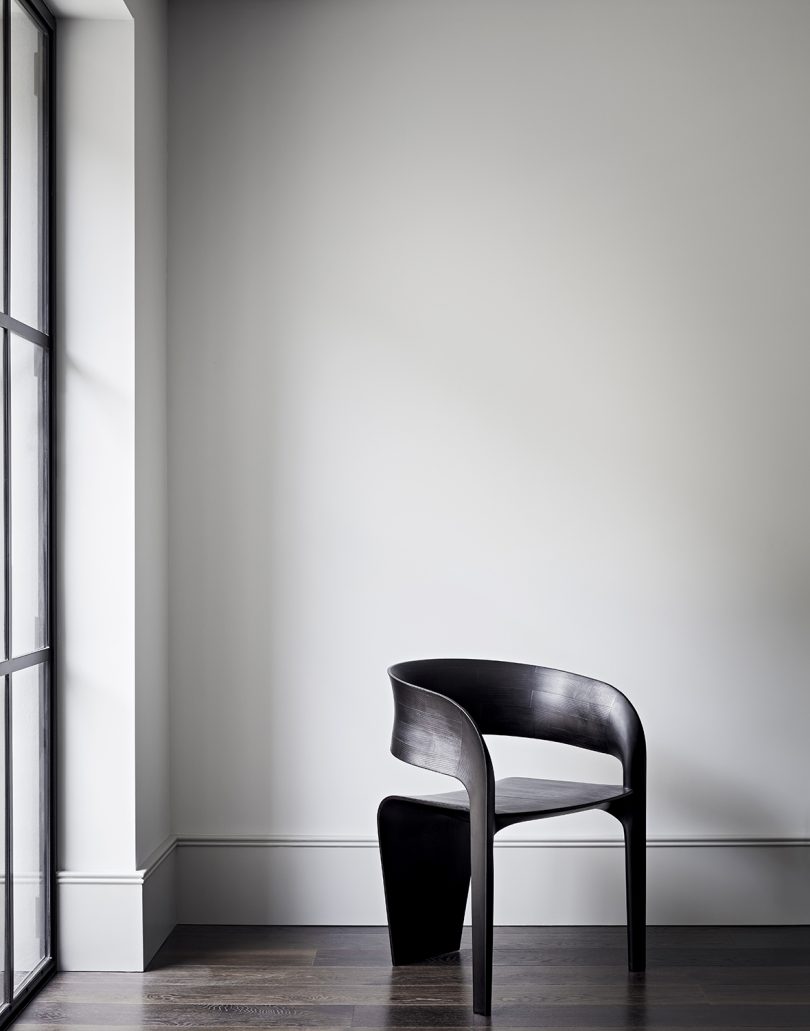 curvaceous wood armchair in white-walled room
