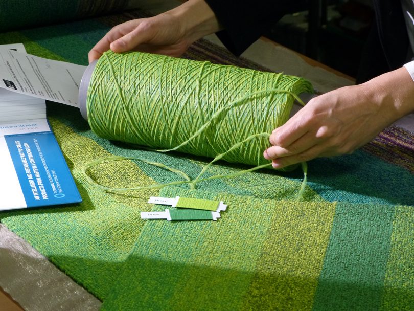 two hands holding a spool of green recycled nylon yarn