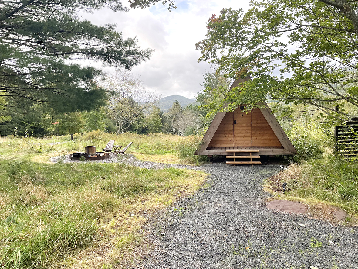 small a-frame cabin with a fire pit in a field