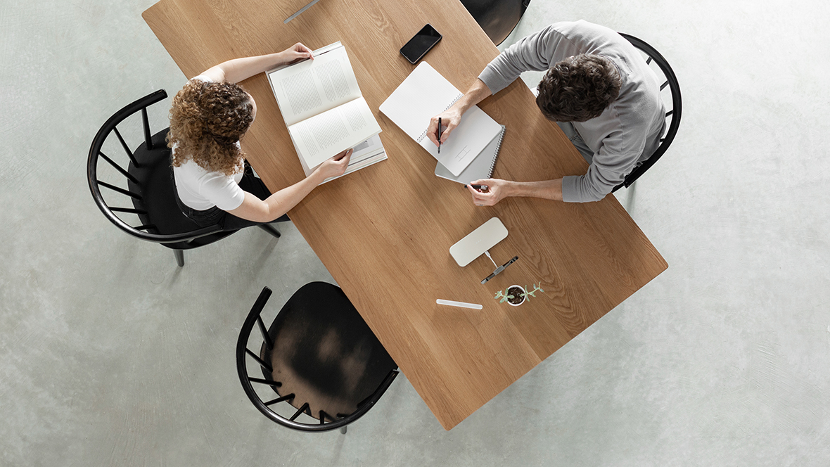 overhead image of table with armchairs and two people perusing books