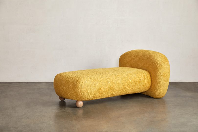 gold chaise in white space with concrete floor