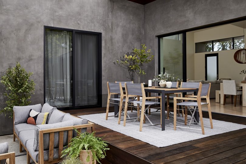styled outdoor dining table with six wood and light grey armchairs