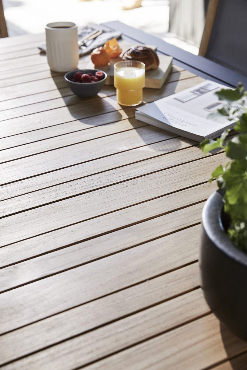 detail of outdoor dining table tabletop with magazine and juice glass