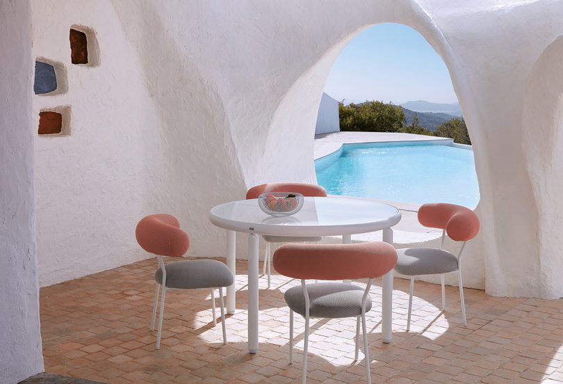 roll back and arm white and coral colored outdoor dining chair in an alcove