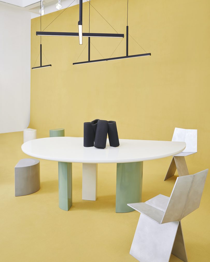 dining table, two dining chairs, one stool, table sculpture, and lighting on butter yellow background